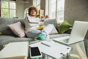 Image showing Manager or student working from home while being insulated or keep quarantine \'cause of coronavirus COVID-19. Reading report, task, sitting on sofa.