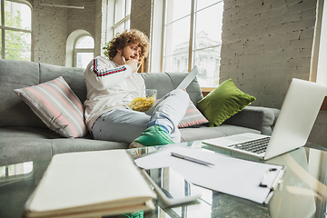 Image showing Manager or student working from home while being insulated or keep quarantine \'cause of coronavirus COVID-19. Reading report, task, sitting on sofa.