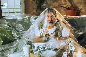 Image showing Senior man covered with plastic, eating fast food and drinking beer - environmental pollution by people concept