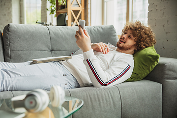 Image showing Manager or student working from home while being insulated or keep quarantine \'cause of coronavirus COVID-19. Scrolling phone lying down on sofa.