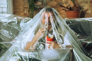 Image showing Senior man covered with plastic, eating fast food and drinking beer - environmental pollution by people concept