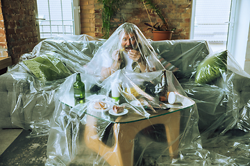 Image showing Senior man covered with plastic, eating fast food and drinking beer - environmental pollution by people concept