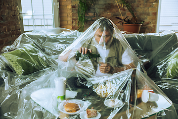 Image showing Senior man covered with plastic, eating fast food and drinking beer - environmental pollution by people concept