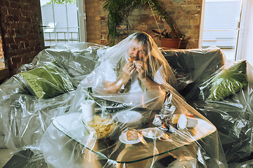 Image showing Senior man covered with plastic, eating fast food and drinking beer - environmental pollution by people concept