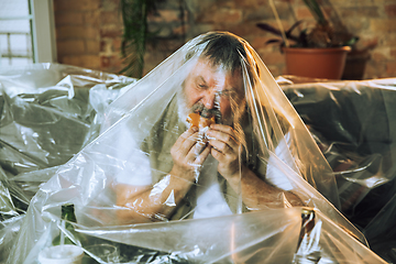 Image showing Senior man covered with plastic, eating fast food and drinking beer - environmental pollution by people concept