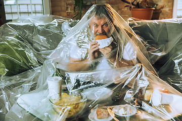 Image showing Senior man covered with plastic, eating fast food and drinking beer - environmental pollution by people concept