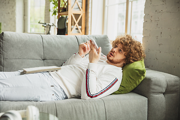 Image showing Manager or student working from home while being insulated or keep quarantine \'cause of coronavirus COVID-19. Recording voice message lying down on sofa.