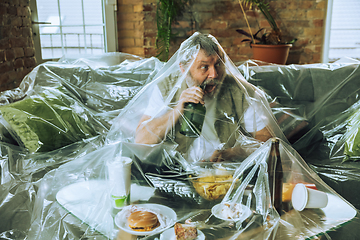 Image showing Senior man covered with plastic, eating fast food and drinking beer - environmental pollution by people concept