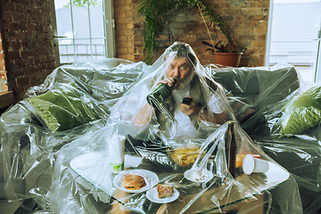 Image showing Senior man covered with plastic, eating fast food and drinking beer - environmental pollution by people concept