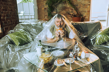 Image showing Senior man covered with plastic, eating fast food and drinking beer - environmental pollution by people concept