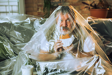 Image showing Senior man covered with plastic, eating fast food and drinking beer - environmental pollution by people concept