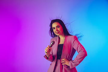 Image showing Caucasian female singer portrait isolated on gradient studio background in neon light