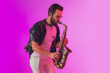 Image showing Young caucasian jazz musician playing the saxophone in neon light