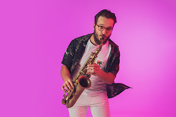 Image showing Young caucasian jazz musician playing the saxophone in neon light