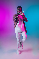 Image showing African-american male singer portrait isolated on gradient studio background in neon light