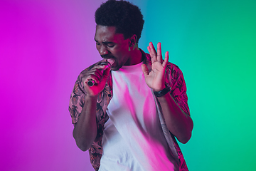 Image showing African-american male singer portrait isolated on gradient studio background in neon light