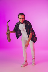 Image showing Young caucasian jazz musician playing the saxophone in neon light