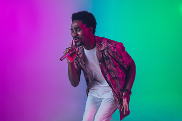 Image showing African-american male singer portrait isolated on gradient studio background in neon light