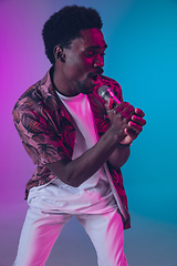 Image showing African-american male singer portrait isolated on gradient studio background in neon light