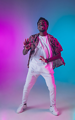 Image showing African-american male singer portrait isolated on gradient studio background in neon light