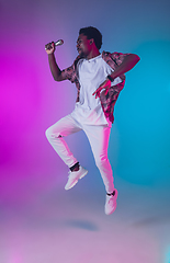 Image showing African-american male singer portrait isolated on gradient studio background in neon light