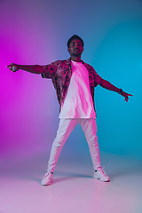 Image showing African-american male singer portrait isolated on gradient studio background in neon light