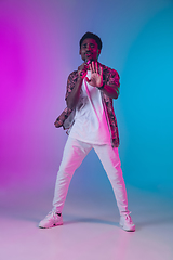 Image showing African-american male singer portrait isolated on gradient studio background in neon light