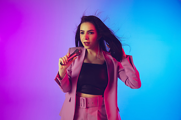 Image showing Caucasian female singer portrait isolated on gradient studio background in neon light