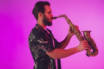 Image showing Young caucasian jazz musician playing the saxophone in neon light