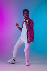 Image showing African-american male singer portrait isolated on gradient studio background in neon light