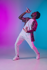 Image showing African-american male singer portrait isolated on gradient studio background in neon light