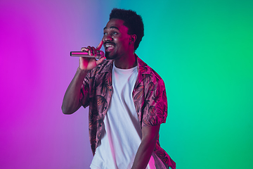 Image showing African-american male singer portrait isolated on gradient studio background in neon light