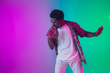 Image showing African-american male singer portrait isolated on gradient studio background in neon light