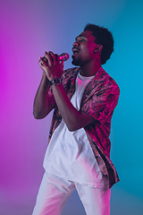 Image showing African-american male singer portrait isolated on gradient studio background in neon light