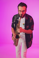 Image showing Young caucasian jazz musician playing the saxophone in neon light