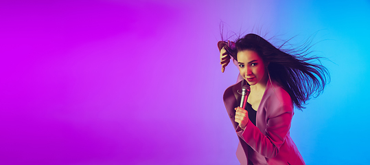 Image showing Caucasian female singer portrait isolated on gradient studio background in neon light, flyer with copyspace for ad