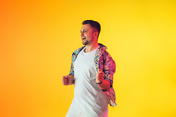 Image showing Young caucasian musician, dancer, party host, DJ on gradient background in neon light