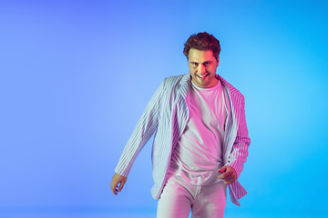 Image showing Young caucasian musician, dancer, party host, DJ on gradient background in neon light