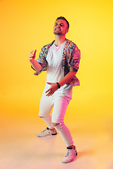 Image showing Young caucasian musician, dancer, party host, DJ on gradient background in neon light