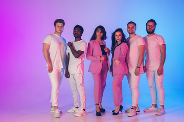 Image showing Group of young multiethnic musicians created band, posing in neon light on gradient background