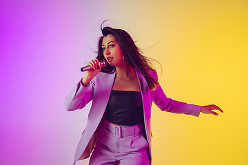 Image showing Caucasian female singer portrait isolated on gradient studio background in neon light