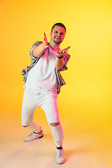 Image showing Young caucasian musician, dancer, party host, DJ on gradient background in neon light