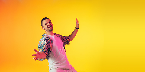 Image showing Young caucasian musician, dancer, party host, DJ on gradient background in neon light, flyer with copyspace for ad