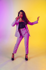 Image showing Caucasian female singer portrait isolated on gradient studio background in neon light