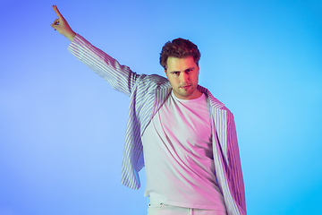 Image showing Young caucasian musician, dancer, party host, DJ on gradient background in neon light