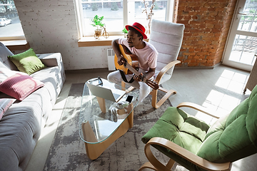 Image showing African-american musician playing guitar during online concert at home isolated and quarantined, impressive improvising