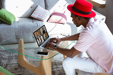 Image showing African-american man during videocall with his band sitting at home, musicians during quarantine and insulation