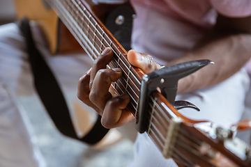 Image showing Close up of african-american musician playing guitar during online concert at home isolated and quarantined, impressive improvising