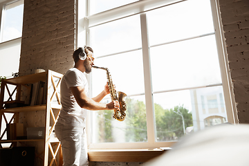 Image showing Caucasian musician playing saxophone during online concert at home isolated and quarantined, impressive improvising