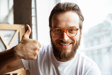 Image showing Caucasian musician greeting audience before online concert at home isolated and quarantined, cheerful, smiling